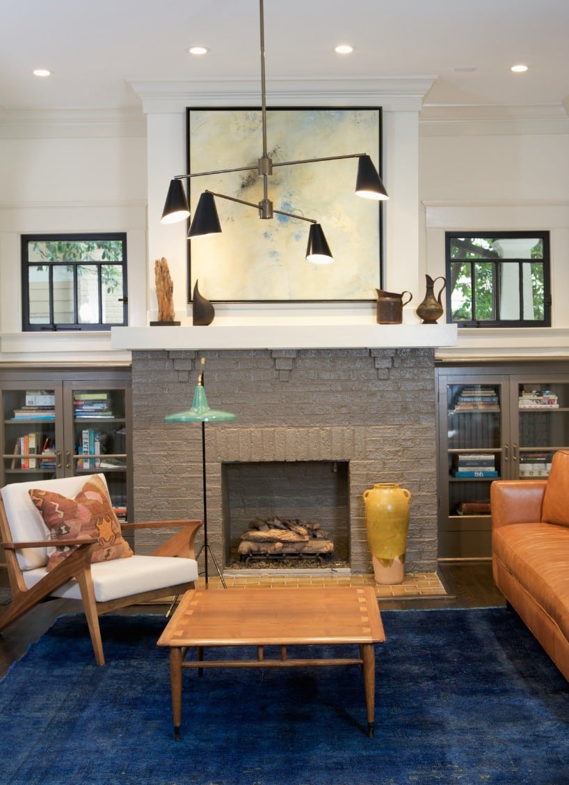 Transitional living room with stone fireplace, built-in cabinets, and decorative pendant light.