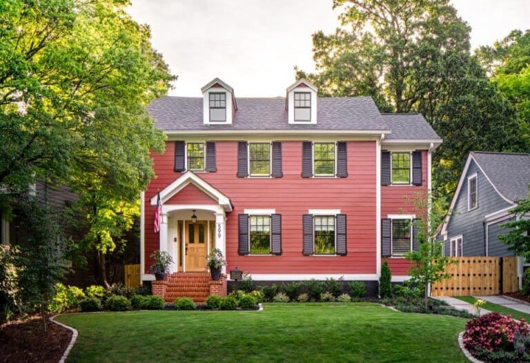 Traditional home exterior with red siding, brick entry stairs, and natural wood front door.