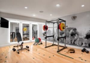 Basement gym design with natural wood flooring, photo wall mural, and backlit full length mirrors.