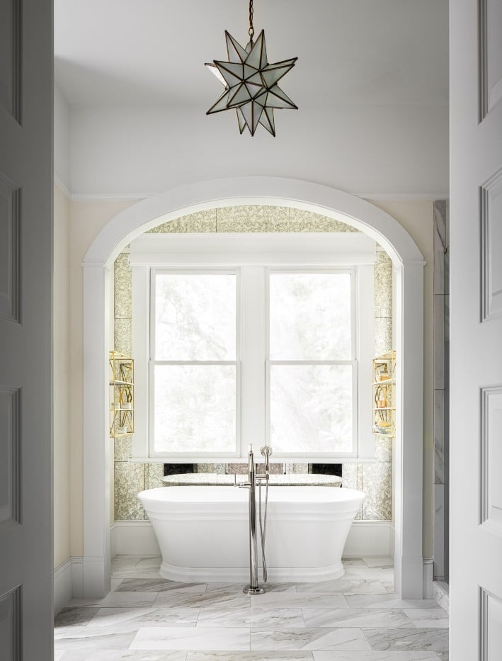 Classic primary bathroom with free standing bathtub and starburst pendant light.