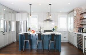 Gourmet kitchen with dark blue island, brick beam accent, and white subway tile.