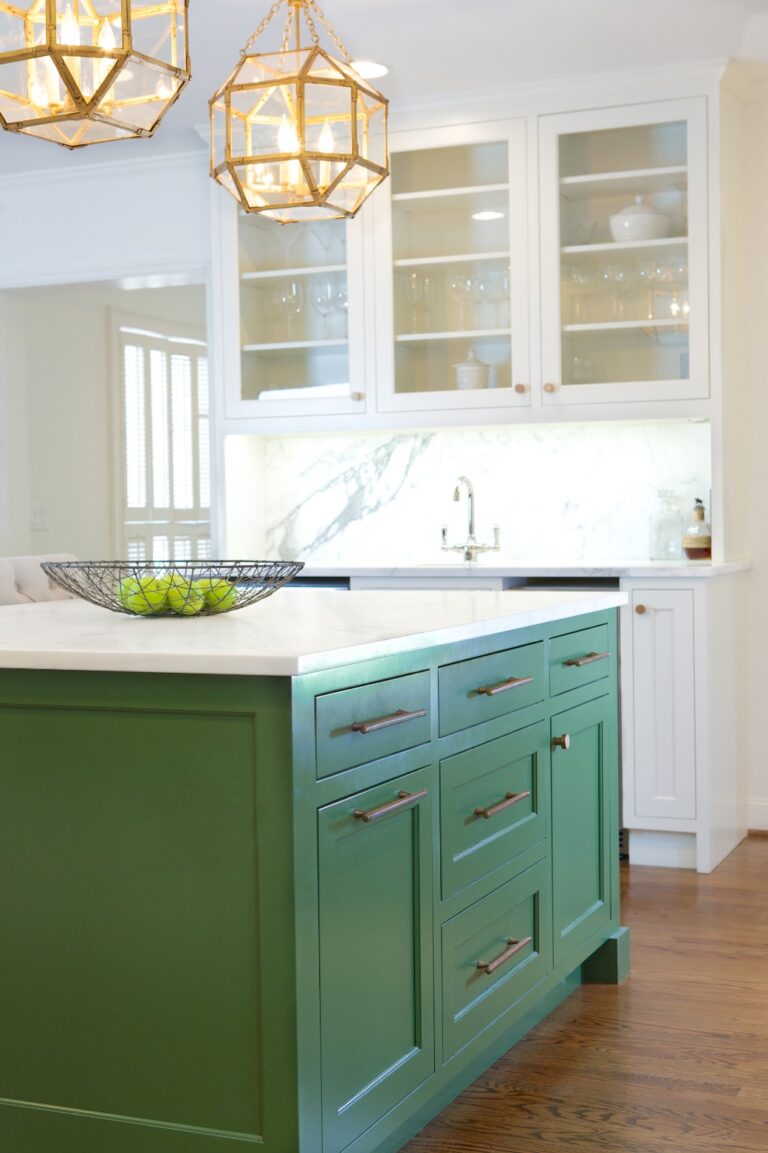 Transitional kitchen with green island, white cabinetry, white subway tile, and brass pendant lights.