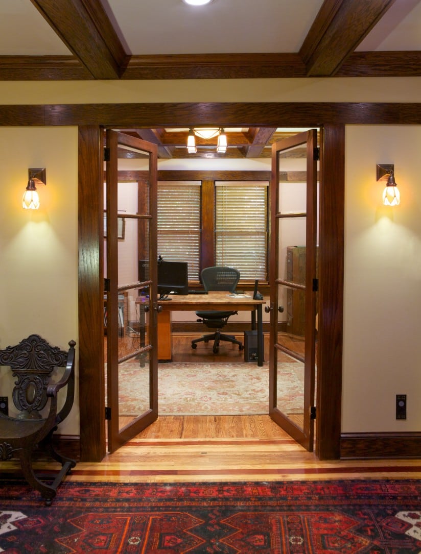 Craftsman style home office entry with natural wood and glass french doors, wood ceiling beams, and natural wood stained floor.