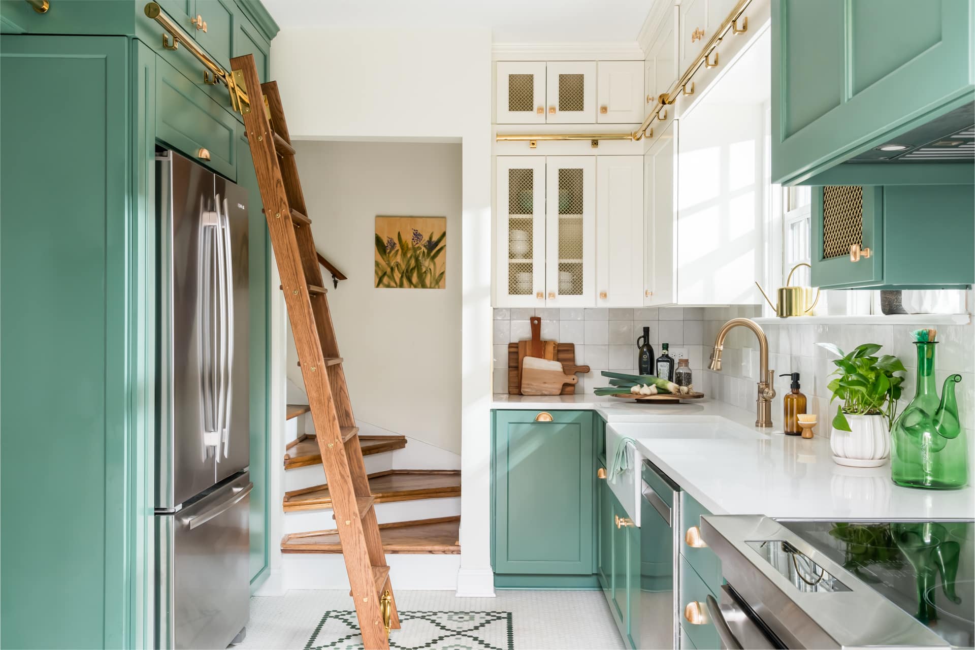 Traditional kitchen with green lower cabinets, white upper cabinets, brass hardware, and natural wood library ladder.