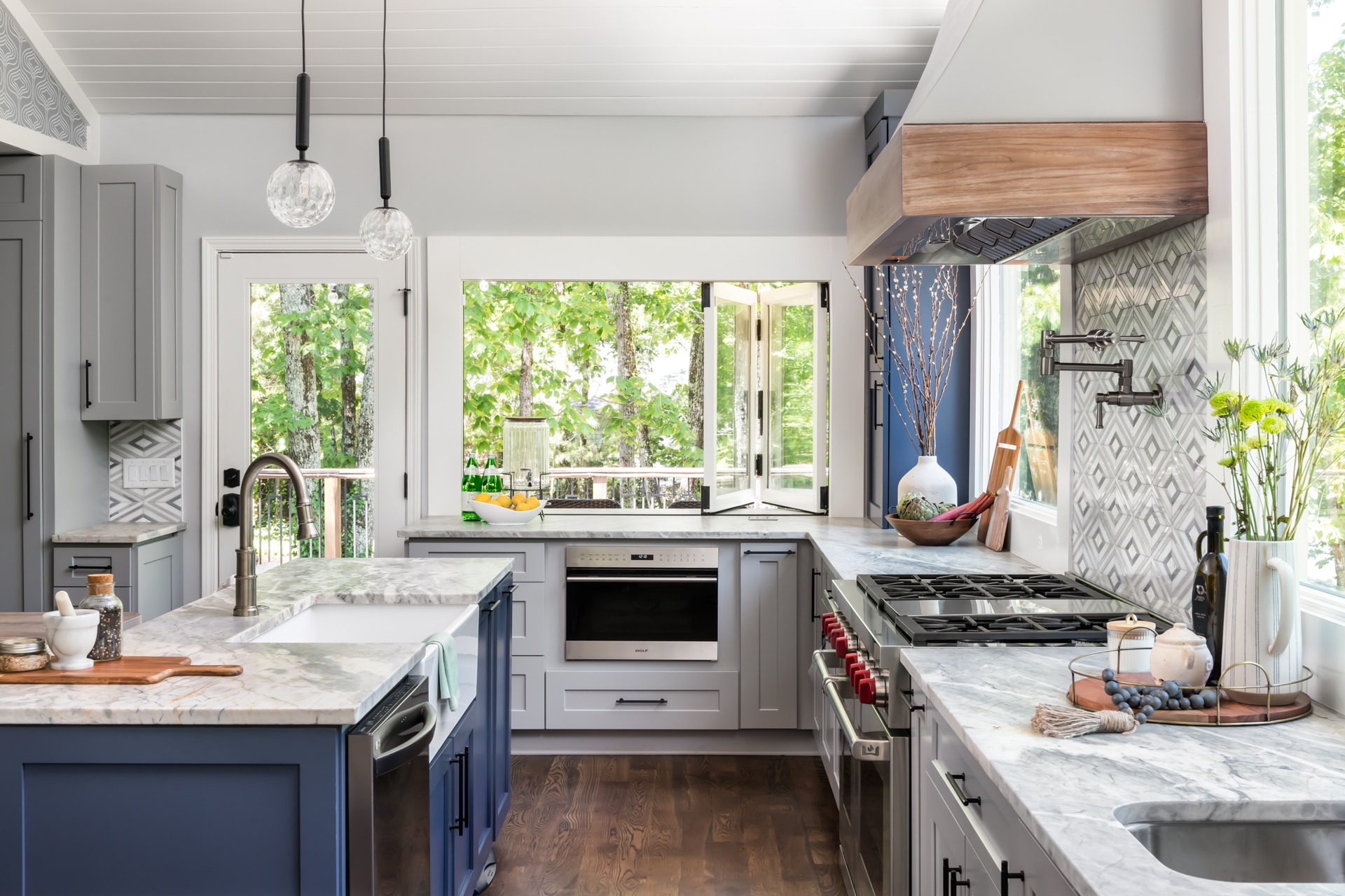 Transitional kitchen with white cabinets, dark blue island, granite countertops, and diamond geometric tile backsplash.