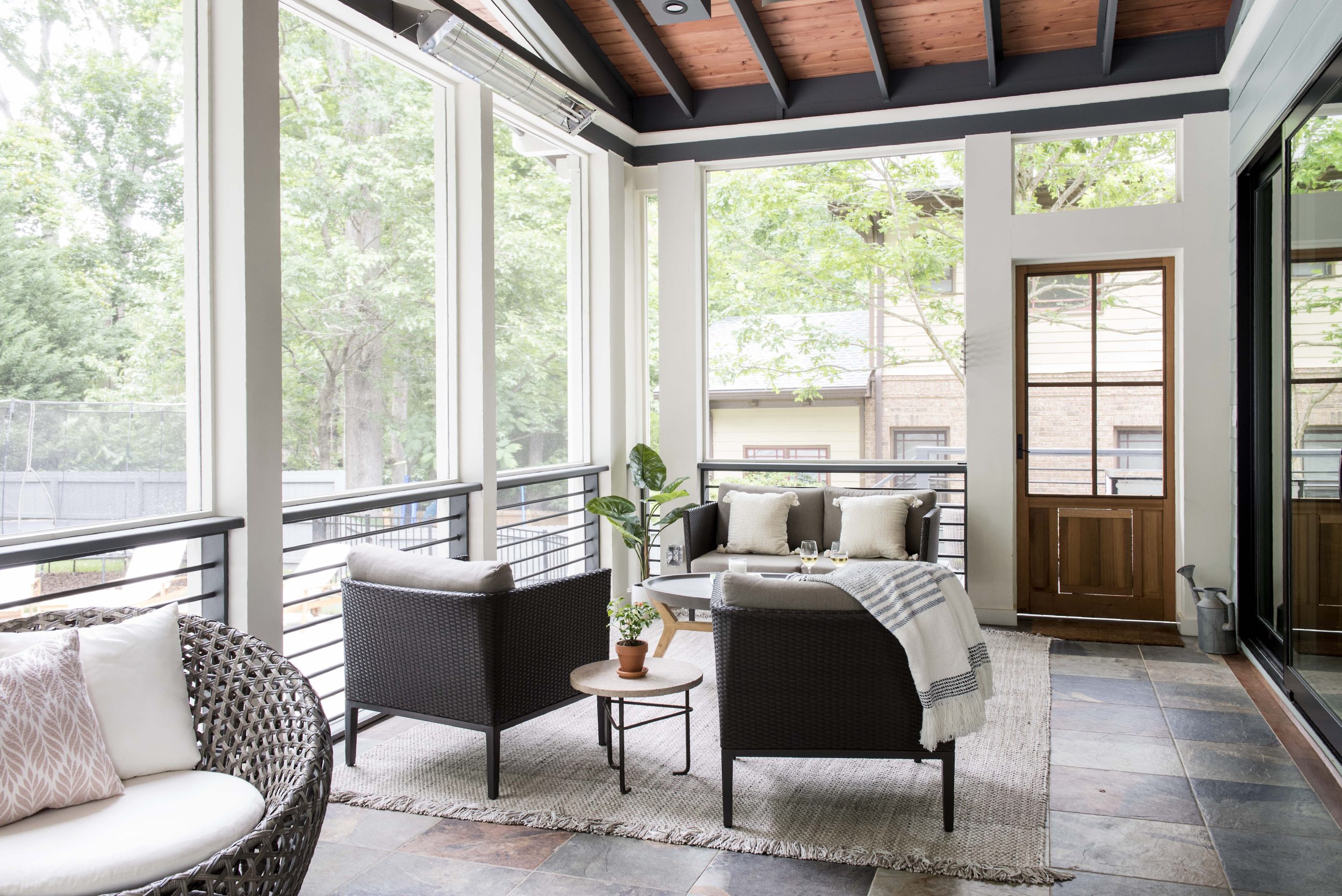 Transitional screened porch with natural stained ceiling, white beams, and granite tile floor.