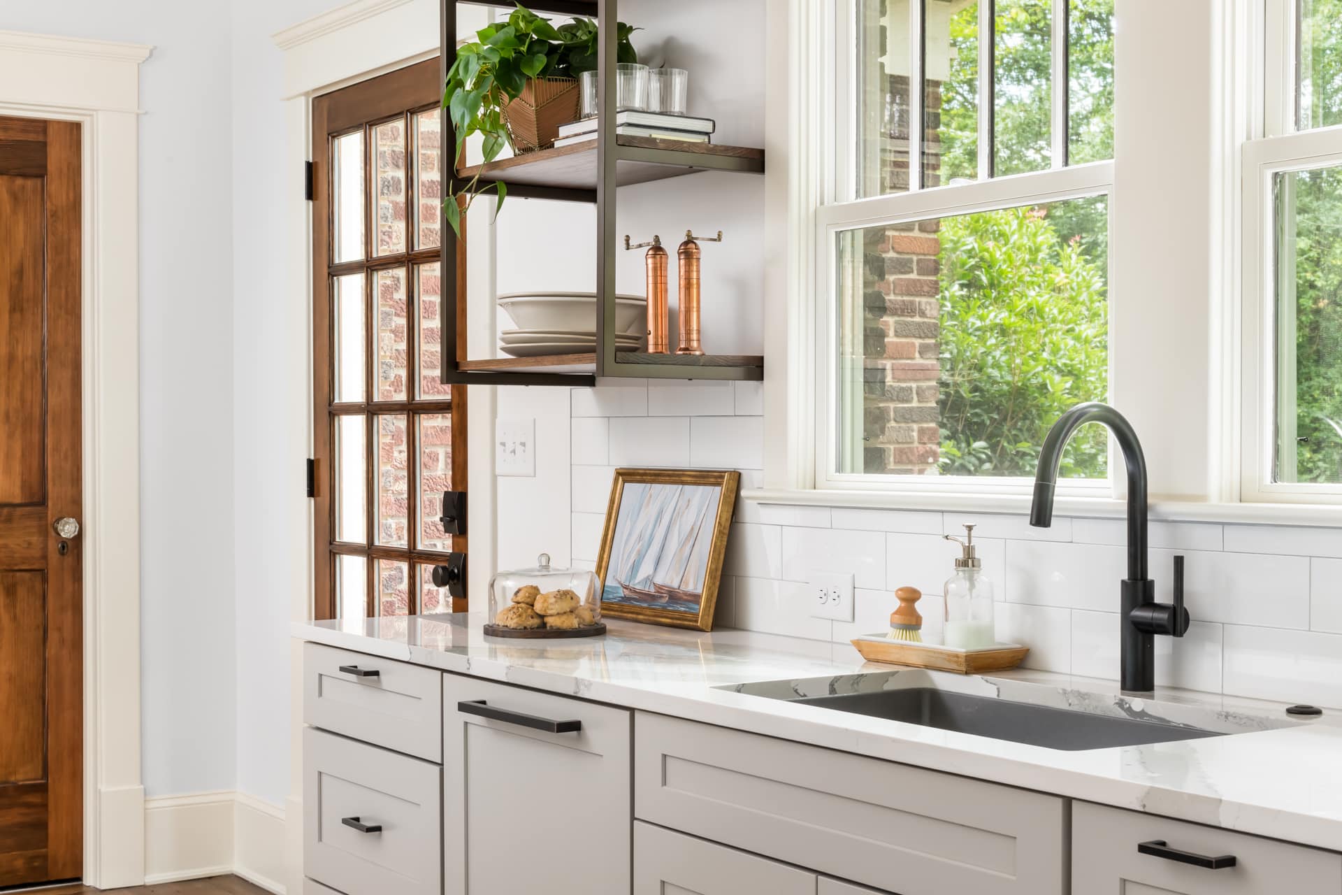 Traditional kitchen design with light gray cabinets, open shelves, granite countertops, and natural wood stained doors.