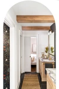 Primary bathroom with double vanities and natural wood ceiling beams